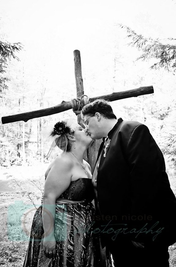 Bride and groom kissing by cross